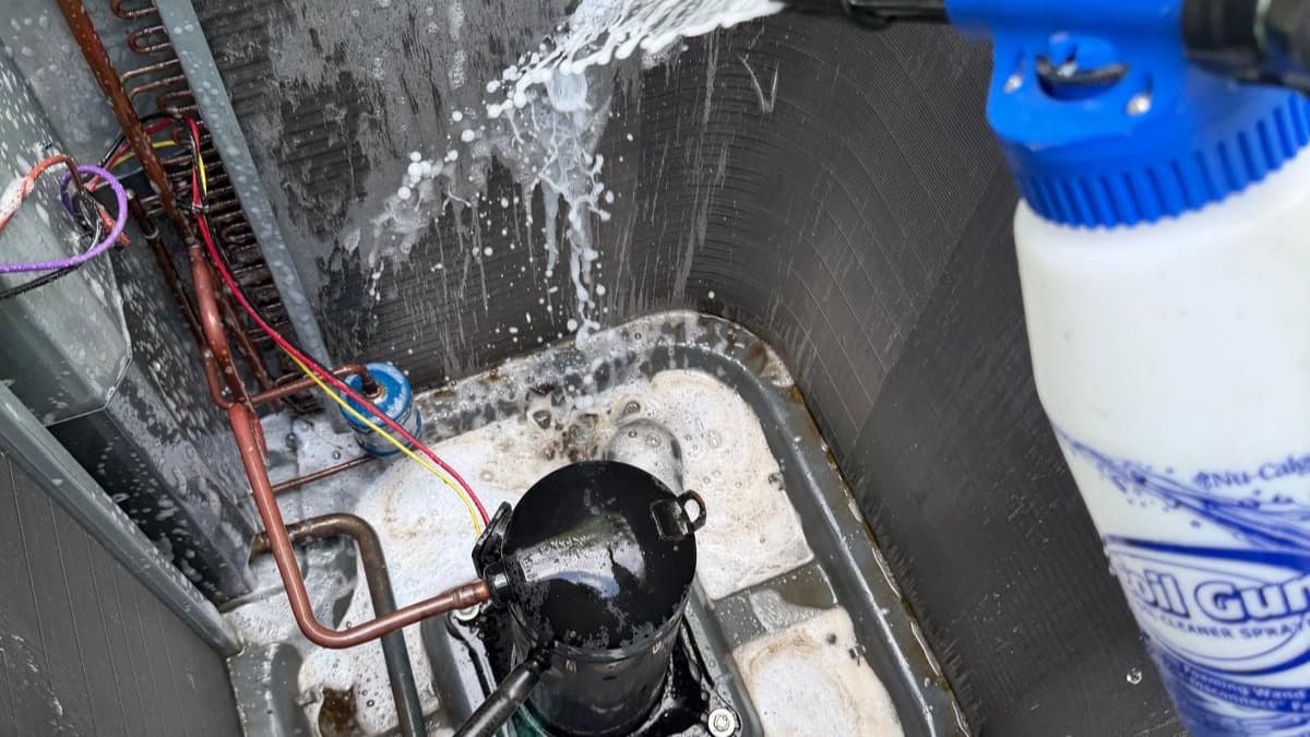 AC Professional Cooling & Heating technician deep-cleaning an AC coil with foaming cleaner during a full tune-up in Cape Coral, FL