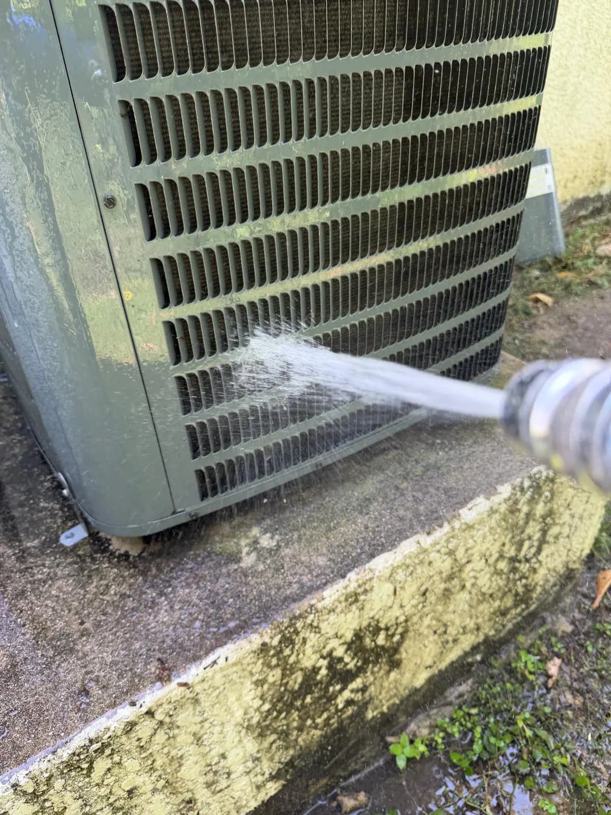 AC Professional technician rinsing a condenser coil during a deep cleaning