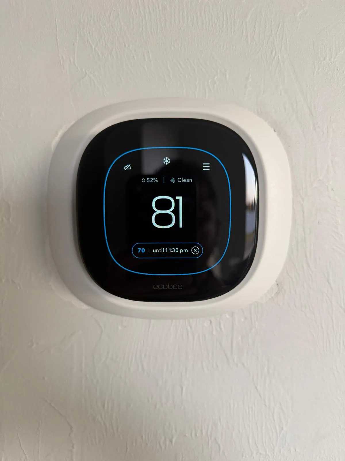 Wall-mounted smart thermostat displaying indoor temperature and humidity