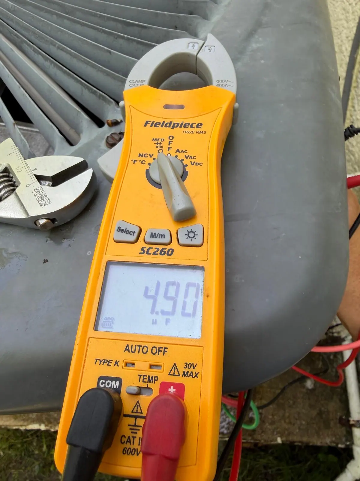 Technician testing an AC capacitor with a multimeter