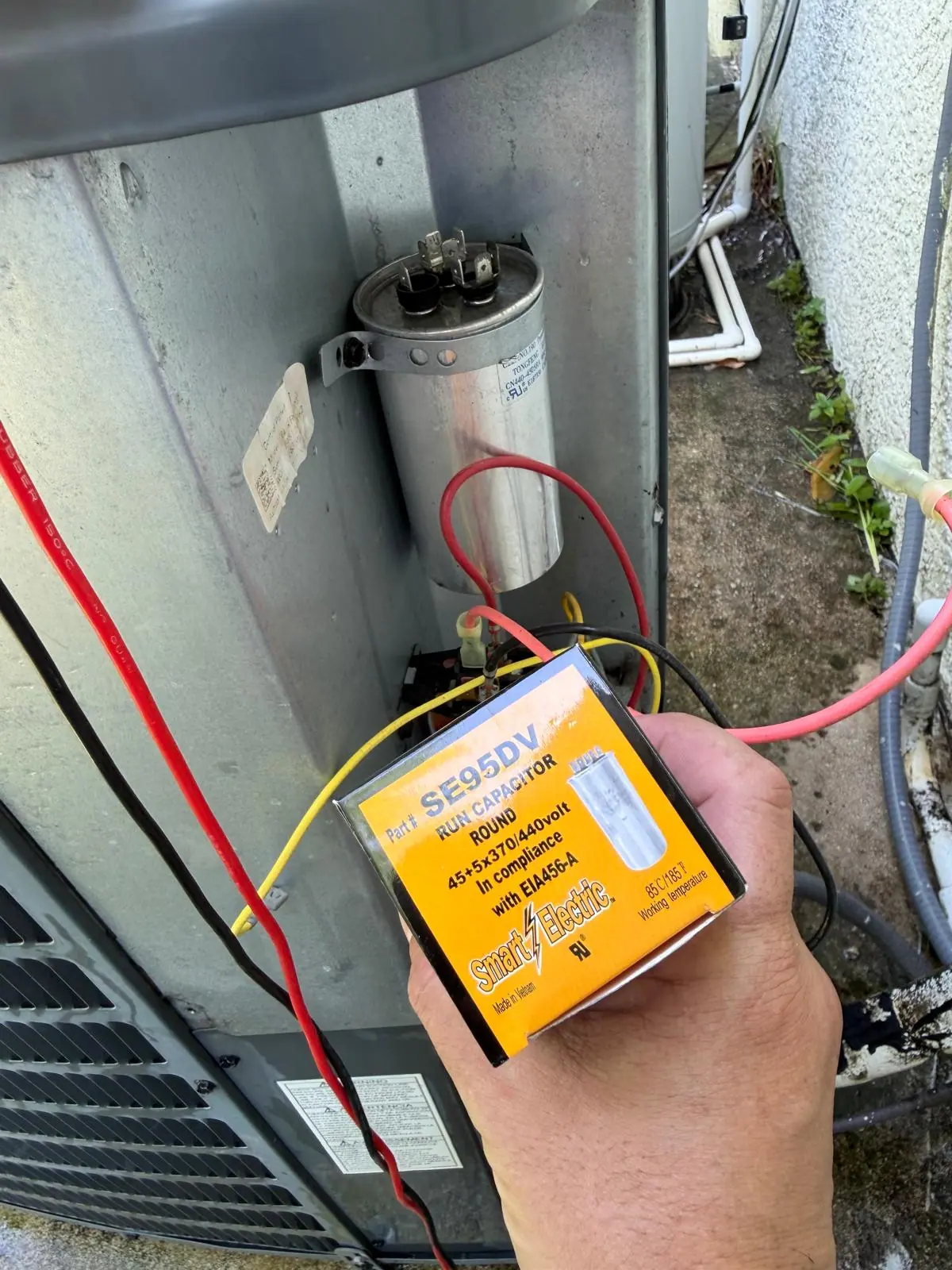 New capacitor being installed on an outdoor AC unit