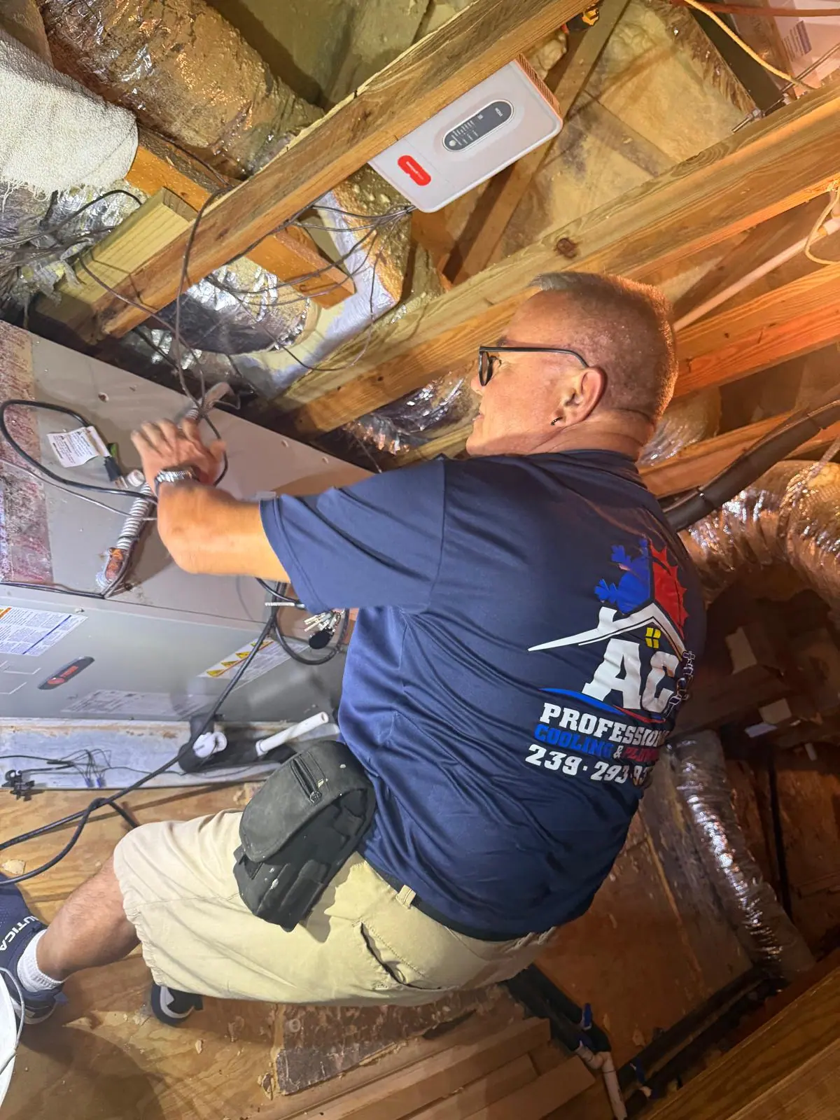 AC Professional technician working in an attic