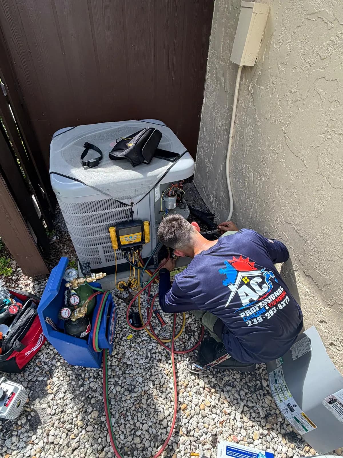 AC Professional technician working on an outdoor AC unit with gauges connected during a service call