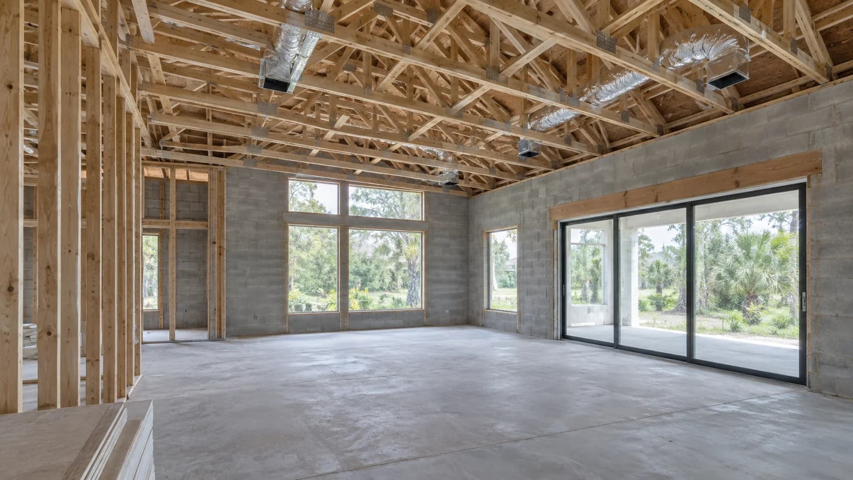 Unfinished living room with large windows and insulated HVAC ducts above the ceiling framing